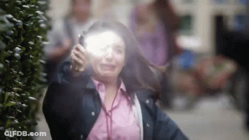 A Woman Is Wearing Headphones And Talking On A Cell Phone While Walking Down The Street . GIF