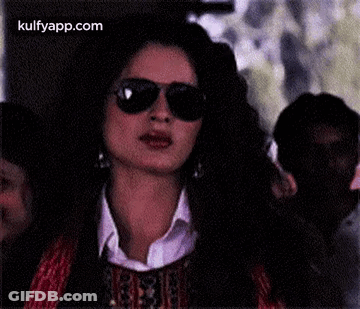 A Woman Is Wearing Sunglasses And A White Shirt . GIF