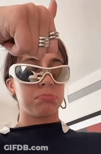 A Woman Is Wearing Sunglasses And Making A Funny Face . GIF