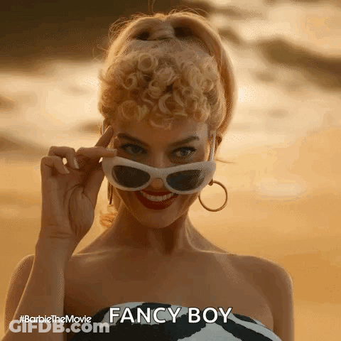 A Woman Is Wearing Sunglasses And Smiling While Standing On A Beach . GIF