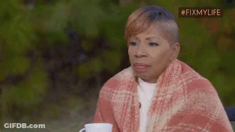 A Woman Is Wrapped In A Blanket And Holding A Cup . GIF