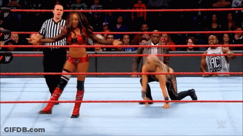A Woman Is Wrestling A Man In A Wrestling Ring While A Referee Looks On . GIF