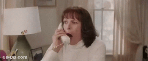 A Woman Is Yawning While Talking On A Phone In A Living Room . GIF