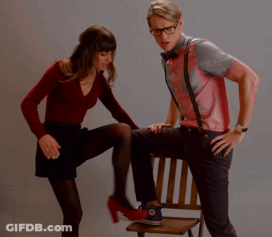 A Woman Kicking A Man 'S Leg Who Is Sitting In A Chair GIF