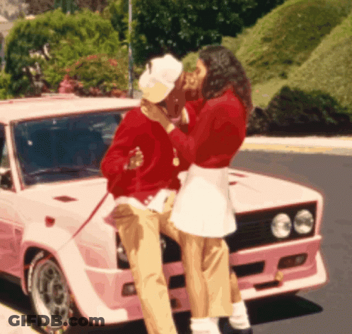 A Woman Kissing A Man On The Cheek In Front Of A Pink Car GIF