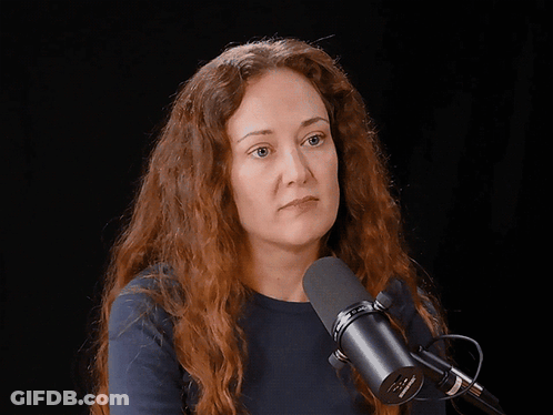 A Woman Laughs In Front Of A Microphone That Says Shure GIF