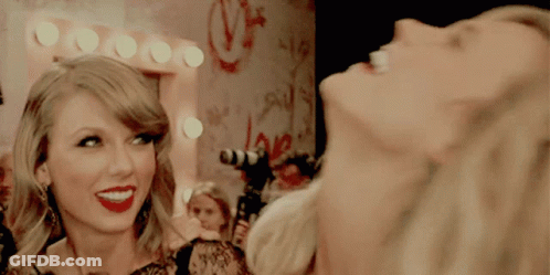 A Woman Laughs In Front Of A Mirror With The Word Love On The Wall GIF