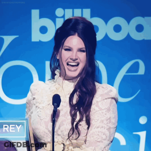 A Woman Laughs In Front Of A Sign That Says Billboard One GIF