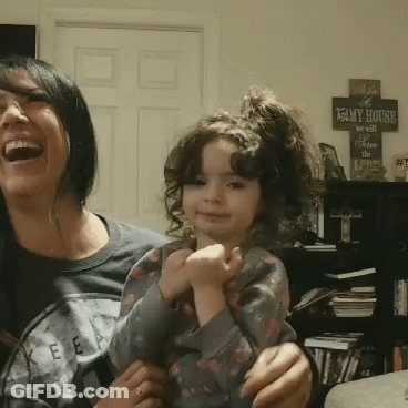 A Woman Laughs While Holding A Little Girl In Front Of A Sign That Reads " My House " GIF