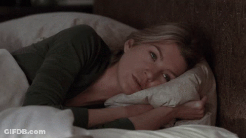 A Woman Laying In Bed With A Pillow On Her Head GIF