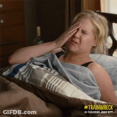 A Woman Laying In Bed With Her Hand On Her Forehead GIF