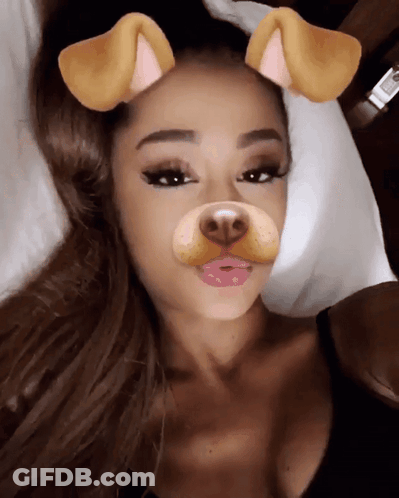 A Woman Laying On A Bed With A Dog Face Filter On Her Face GIF