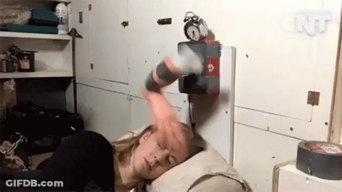 A Woman Laying On A Bed With An Alarm Clock On The Wall Above Her GIF