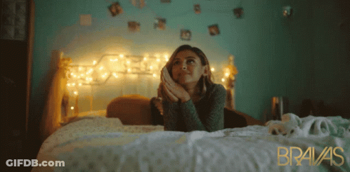 A Woman Laying On A Bed With Bravas Written In Gold GIF