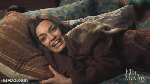 A Woman Laying On A Bed With Ella Mccay On The Bottom GIF