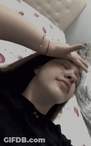 A Woman Laying On A Bed With Her Hand On Her Head GIF