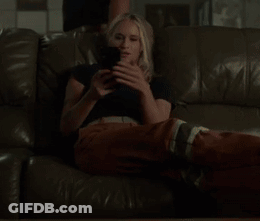 A Woman Laying On A Couch Looking At Her Phone GIF