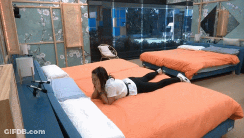 A Woman Laying On Her Stomach On A Bed In A Hotel Room GIF
