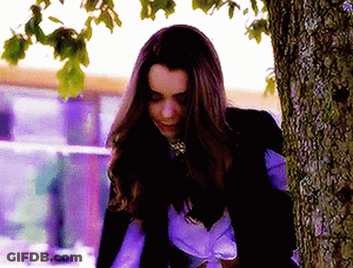 A Woman Leaning Against A Tree Trunk With Her Eyes Closed GIF