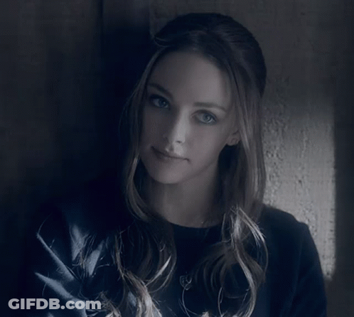 A Woman Leaning Against A Wall With A Serious Look On Her Face GIF