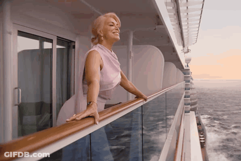 A Woman Leaning On A Railing Looking Out Over The Ocean GIF
