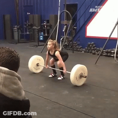 A Woman Lifts A Barbell In A Gym With A Sign That Says ' Awesome ' On It GIF