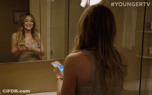 A Woman Looking At Herself In A Bathroom Mirror With #Youngertv On The Bottom GIF