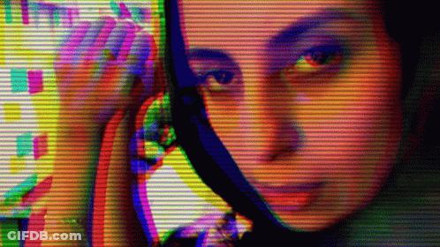 A Woman Looking At Herself In A Mirror With A Rainbow Colored Background GIF