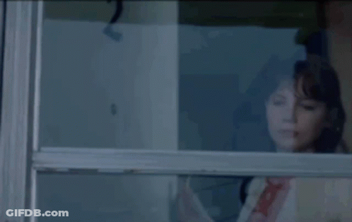 A Woman Looking Out Of A Window With A Reflection Of The Number 2 GIF