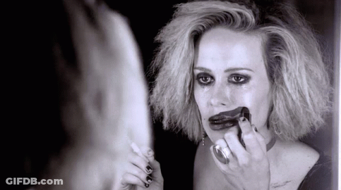 A Woman Looks At Herself In A Mirror With Lipstick On Her Lips GIF