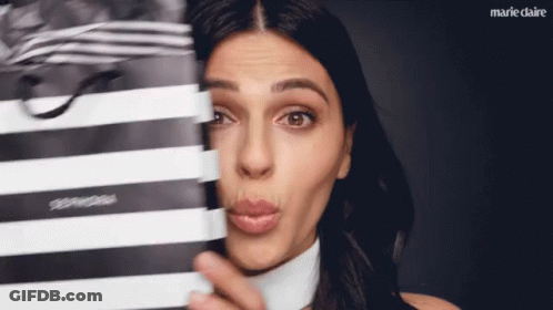 A Woman Making A Face Behind A Black And White Striped Bag GIF