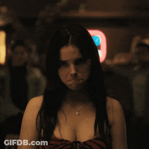 A Woman Making A Funny Face In Front Of A Neon Sign That Says 8 GIF
