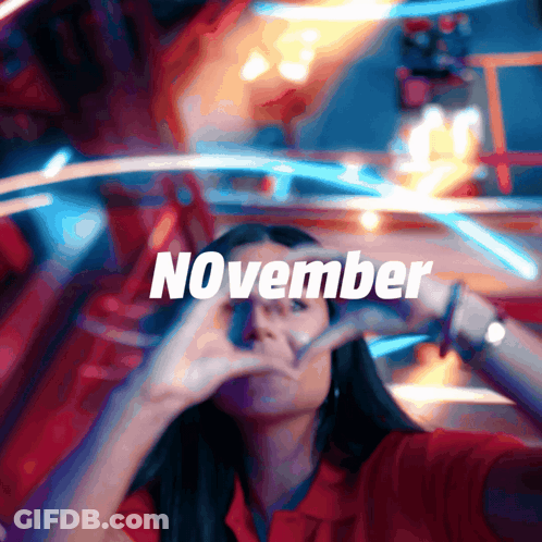 A Woman Making A Heart Shape With Her Hands In Front Of A Sign That Says November GIF