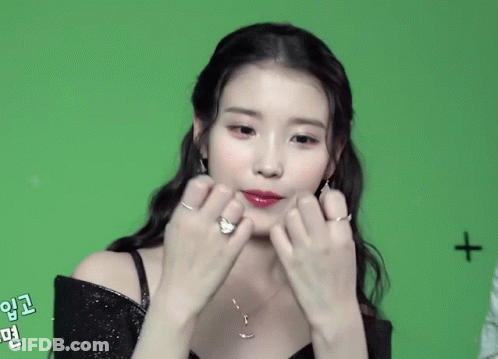 A Woman Making A Heart Shape With Her Hands With A Cross In The Background GIF