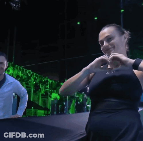 A Woman Making A Heart With Her Hands In A Dark Room GIF