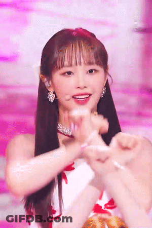 A Woman Making A Heart With Her Hands On A Stage GIF