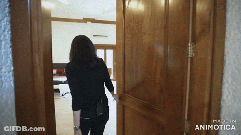 A Woman Opens A Wooden Door With The Words Made In Animatica On The Bottom GIF