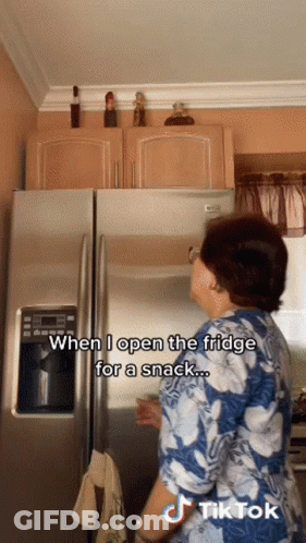 A Woman Opens The Fridge For A Snack With A Tiktok Watermark GIF