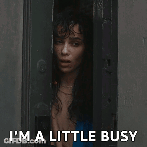 A Woman Peeking Out Of A Door With The Words " I 'M A Little Busy " Above Her GIF