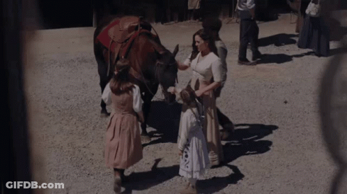 A Woman Petting A Horse While A Little Girl Stands Next To It GIF