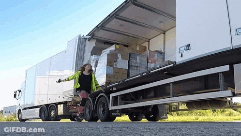 A Woman Pushes A Dolly In Front Of A Semi Truck That Says ' Martin ' On The Side GIF