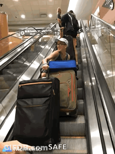 A Woman Pushes Her Luggage Up An Escalator With The Words " Momento Safe " On The Bottom Right GIF