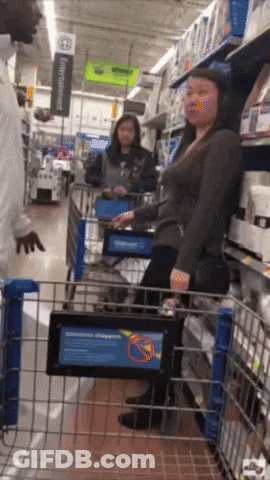 A Woman Pushing A Shopping Cart In A Store With A Sign That Says No Pets GIF