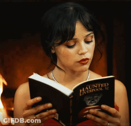 A Woman Reads A Book Titled Haunted Liverpool 12 GIF