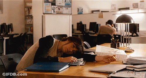 A Woman Rests Her Head On A Desk With A Blue Folder On It That Says ' A ' On It GIF