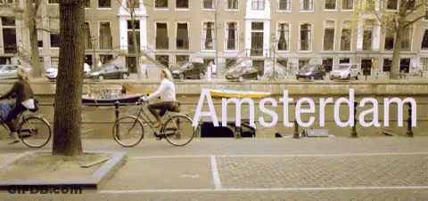 A Woman Riding A Bike Down A Street With The Word Amsterdam Written On It GIF