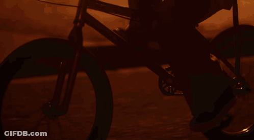A Woman Riding A Bike In Front Of A Sign That Says ' E ' On It GIF