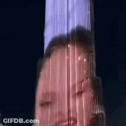 A Woman 'S Face Is Projected Onto A Tall Building At Night GIF