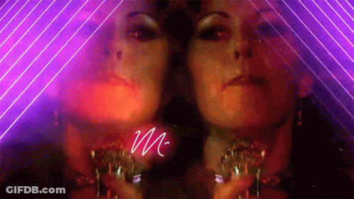 A Woman 'S Face Is Reflected In A Mirror With The Letter M Written In White GIF