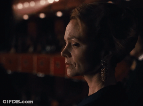 A Woman 'S Face Is Shown In A Dark Room With A Sign That Says ' A ' On It GIF